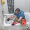 A man performs drain cleaning services.